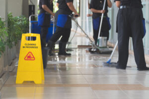 A team of professional cleaners cleaning the floors of an El Paso office space with a yellow sign on the ground reading “CLEANING IN PROGRESS.”