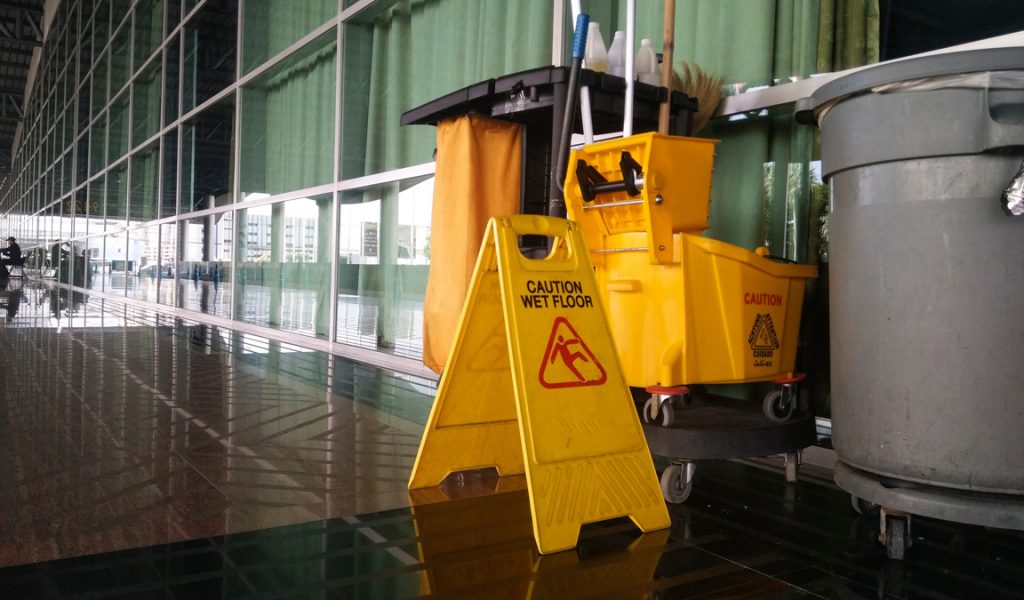 A hallway in an El Paso office with yellow “caution” signs with janitorial supplies.