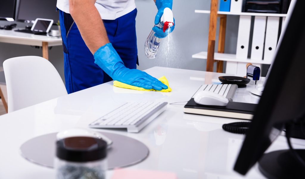 A person spraying an office desk with a cleaner in El Paso.