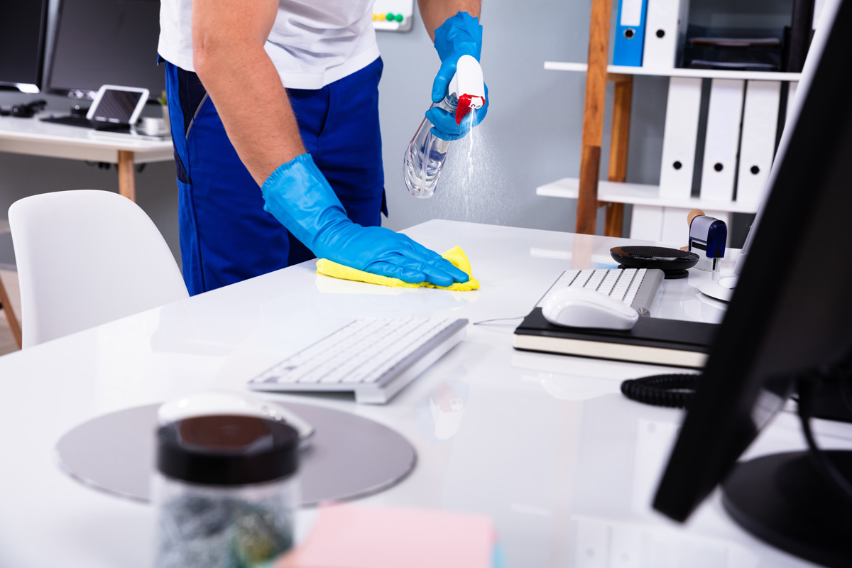 A person spraying an office desk with a cleaner in El Paso.